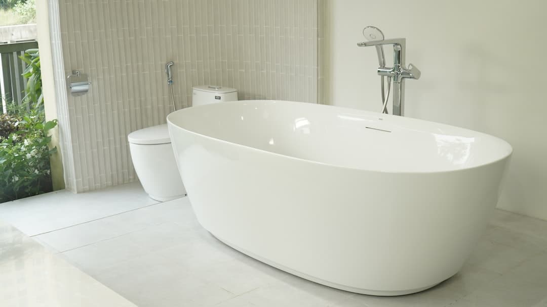 vasca freestanding in solid surface bianco opaco su pavimento in marmo con rubinetteria ottone