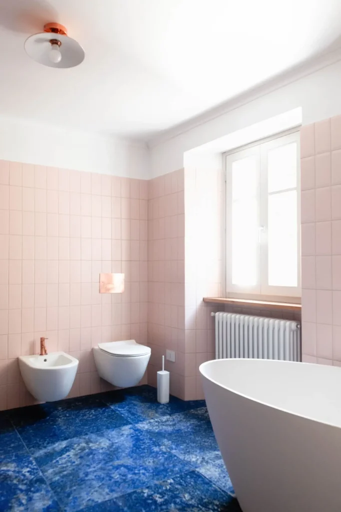 angolo bagno con sanitari sospesi, pavimento blu mare effetto marmo e vasca freestanding