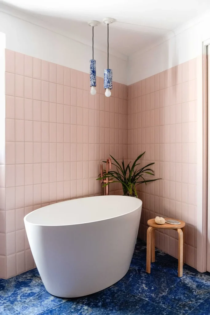 angolo relax del bagno con vasca freestanding, pareti rosa blush su pavimento marmo blu scuro