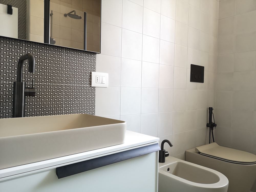bagno moderno in bianco e sabbia con accessori e rubinetteria nera